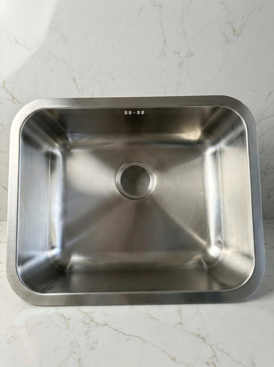 Stainless steel kitchen sink on a white marble countertop