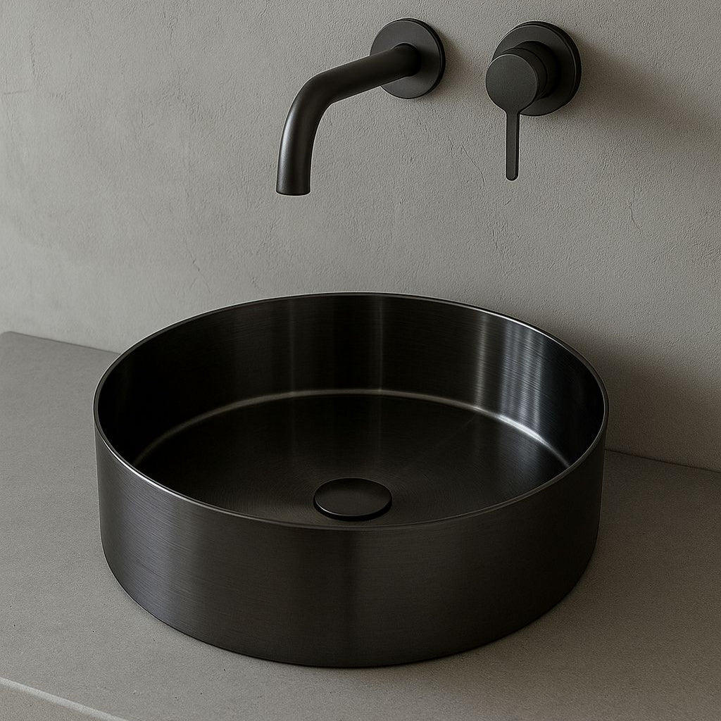 Black gunmetal round sink with faucet on a gray wall